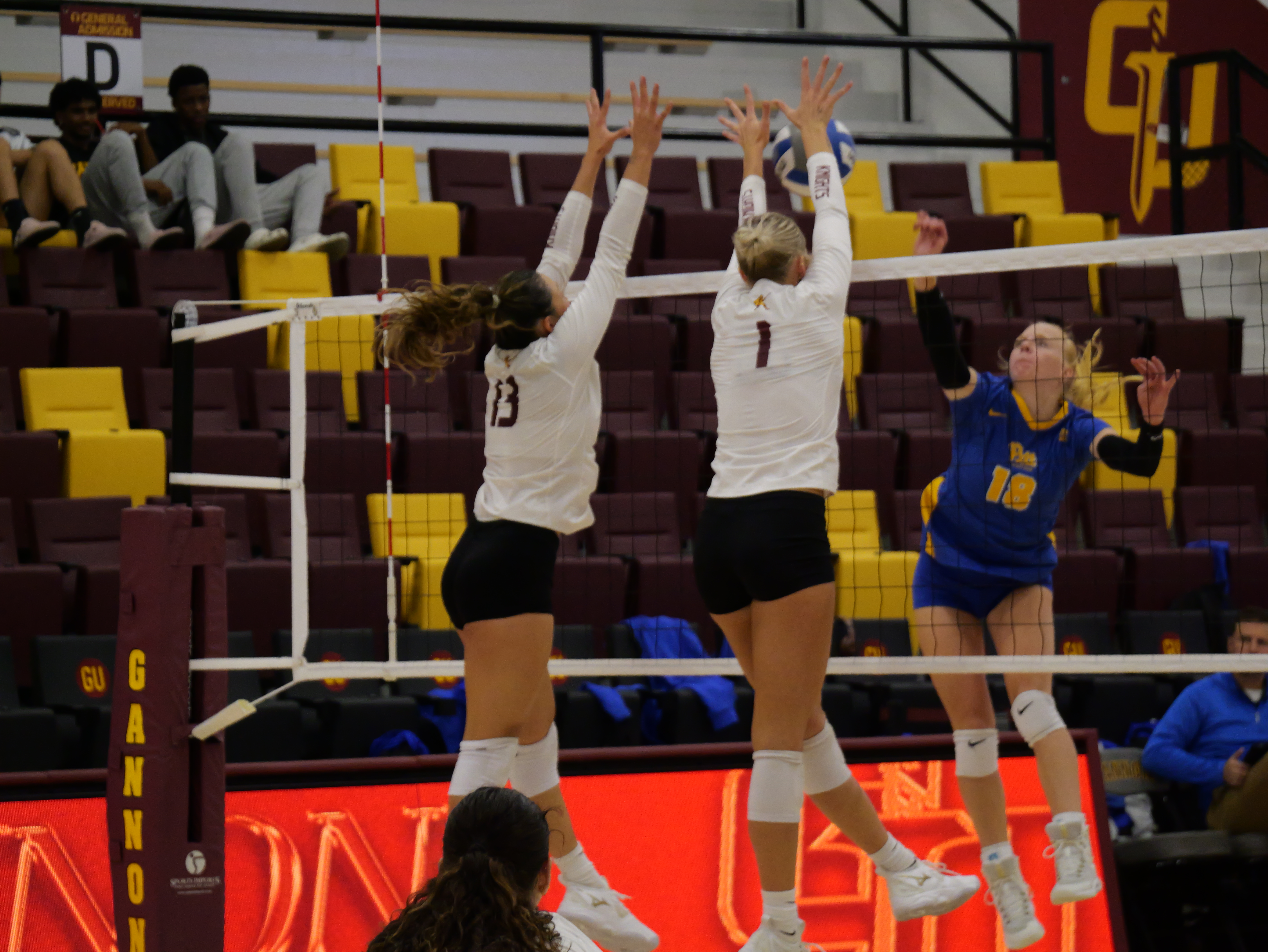 Two players at the net with arms raised in a double block